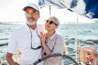 Smiling couple standing on boat in sea