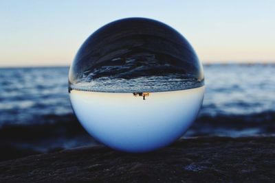 Close-up of ice cream on rock at beach against sky