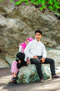 Full length of couple sitting on rock
