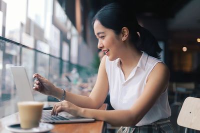 Young woman using mobile phone at table