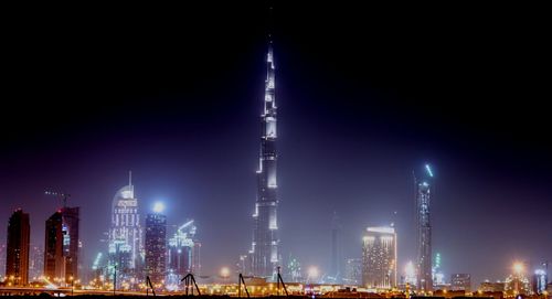 Illuminated modern buildings against sky at night