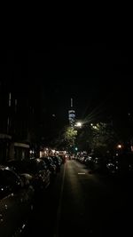 Illuminated street amidst buildings in city at night