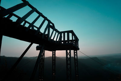 Low angle view of silhouette metallic structure against sky