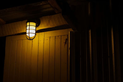 Low angle view of illuminated light bulb hanging on ceiling