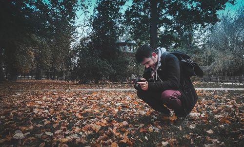 Young man sitting on leaves during autumn