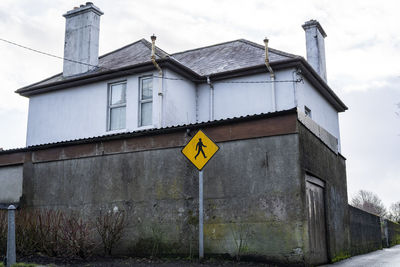 Road sign by building against sky