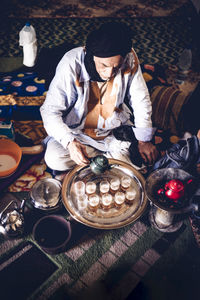 Senior man in smara refugee camp pouring tea into glasses, tindouf, algeria