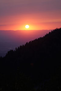 Scenic view of silhouette mountains against orange sky