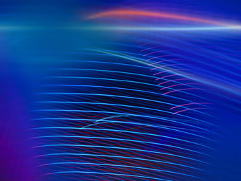 Full frame shot of illuminated light trails against blue background