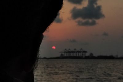 Silhouette beach by sea against sky during sunset