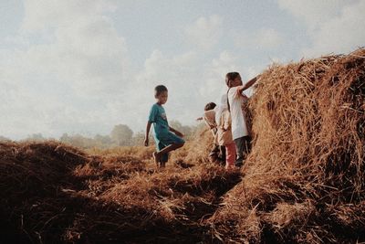 Children standing on field against sky