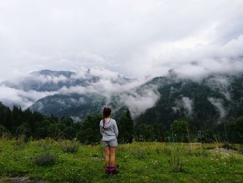 Rear view of man standing on mountain against sky