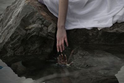 Midsection of woman reaching water in lake