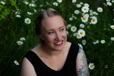Portrait of a smiling young woman against white flowering plants