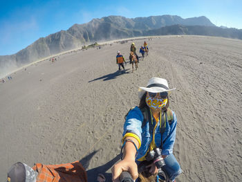 Woman horseback riding at desert during sunny day