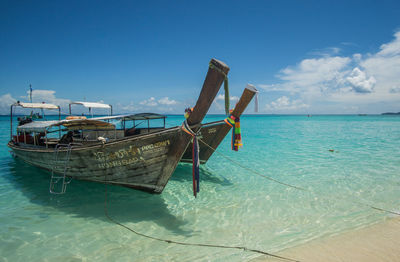 Fishing boats moored on sea against sky