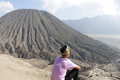 Rear view of man on mountain against sky