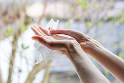 Cropped image of woman cleaning hands with tissue paper