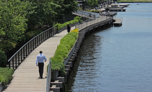 Rear view of man walking on footbridge over milwaukee river