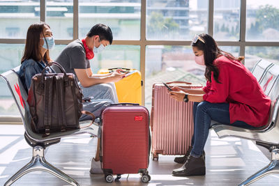 Young asian passengers in face mask on waiting departure seats in terminal airport. 