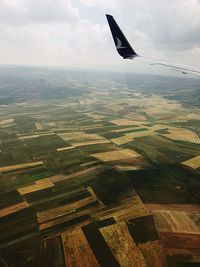 Aerial view of airplane flying over landscape against sky