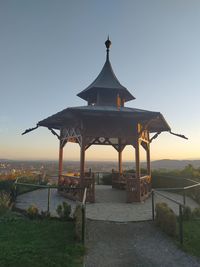 Gazebo by building against clear sky during sunset