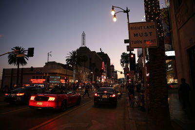 Cars on street by illuminated buildings in city at night