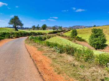 Road amidst field against sky