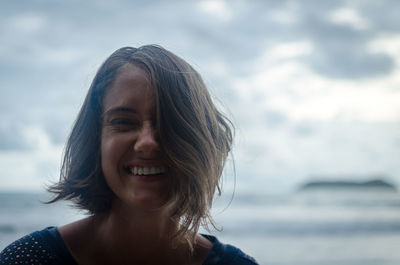 Portrait of smiling woman against sea at beach