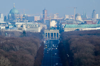 High angle view of road amidst trees leading towards brandenburg gate in city