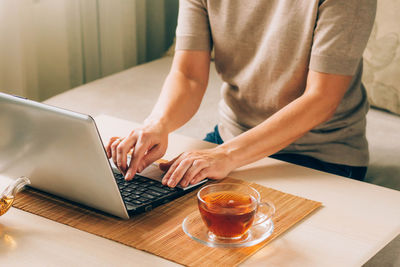 Midsection of man using laptop on table