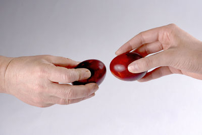 Close-up of hand holding strawberry over white background