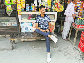 Full length of man sitting on bench at market