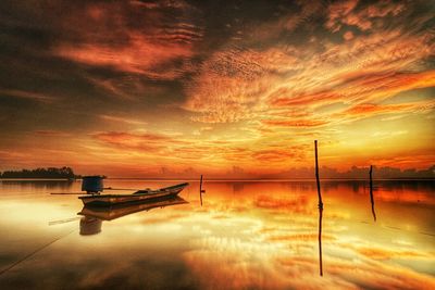 Scenic view of lake against cloudy sky during sunset