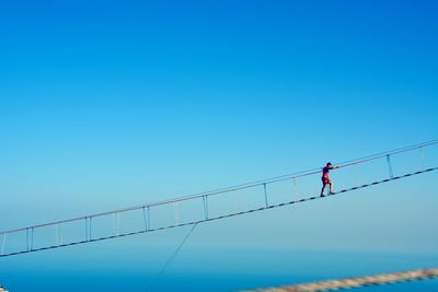 Low angle view of power lines against clear blue sky