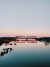 Bridge over river against sky during sunset