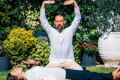 Reiki energy healing. woman lying with her eyes closed, reiki practitioner above her body.