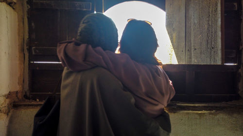 Rear view of couple standing against window