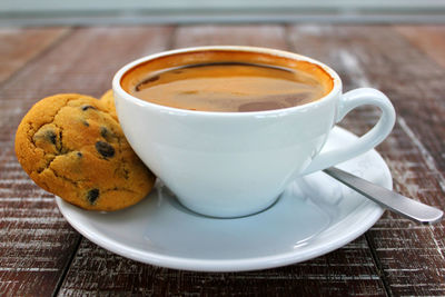 Close-up of coffee cup with chocolate chip cookies on table