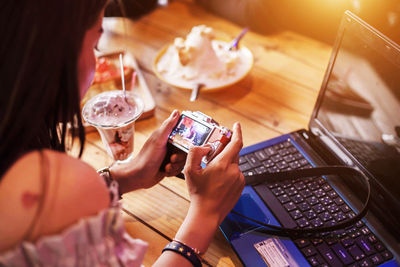 High angle view of woman holding camera while sitting in cafe