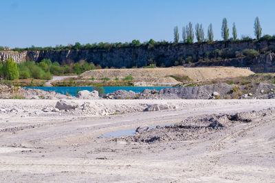 Scenic view of rocks on field against clear blue sky