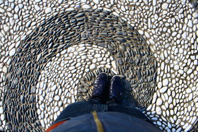 Low section of man standing on cobblestone footpath with swirl pattern