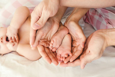 Close-up of hands holding baby feet lying on bed