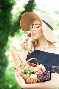 Beautiful woman eating strawberry while holding basket