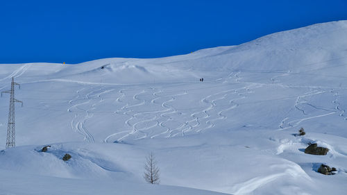 Scenic view of snowcapped mountains with skiers trails