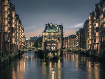 Canal amidst buildings against sky at night