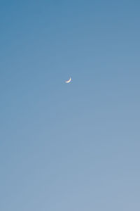 Low angle view of moon against clear blue sky