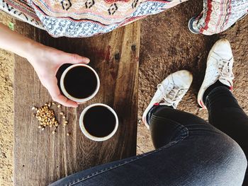 Low section of woman standing by coffee cup