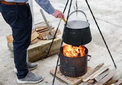 Man cooking stew in cast iron boiler over fire