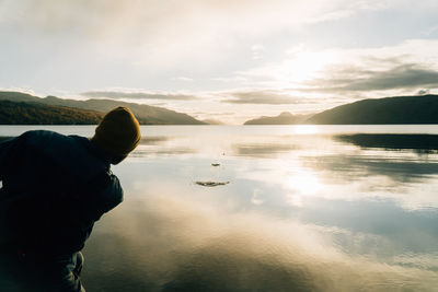 Rear view of man standing against sky during sunset